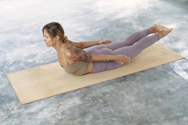 Kvinna övar avancerad yoga på organisk matta. En serie Yogaställen. Tropisk bakgrund — Stockfoto