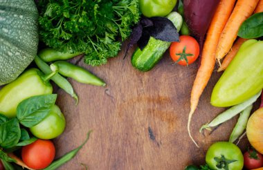 Tahta karatahtanın üstündeki bahçelerden taze hasat. Havuç, domates, biber, salatalık, soğan, kabak, turp, maydanoz..