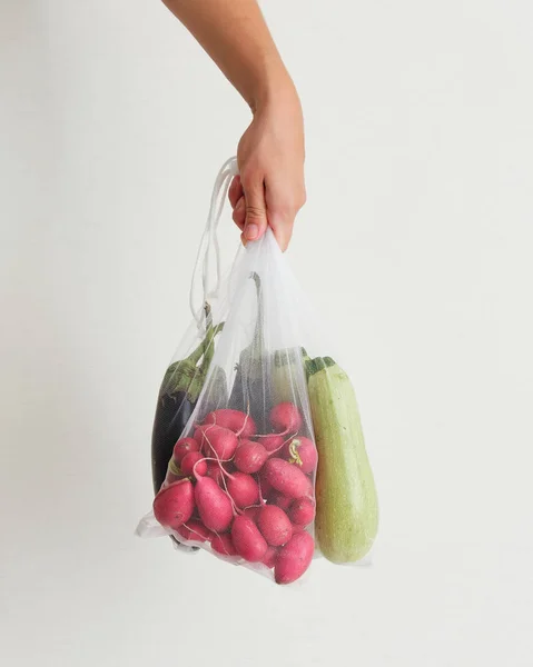 Hand Holding String Bag with Vegetables Side View