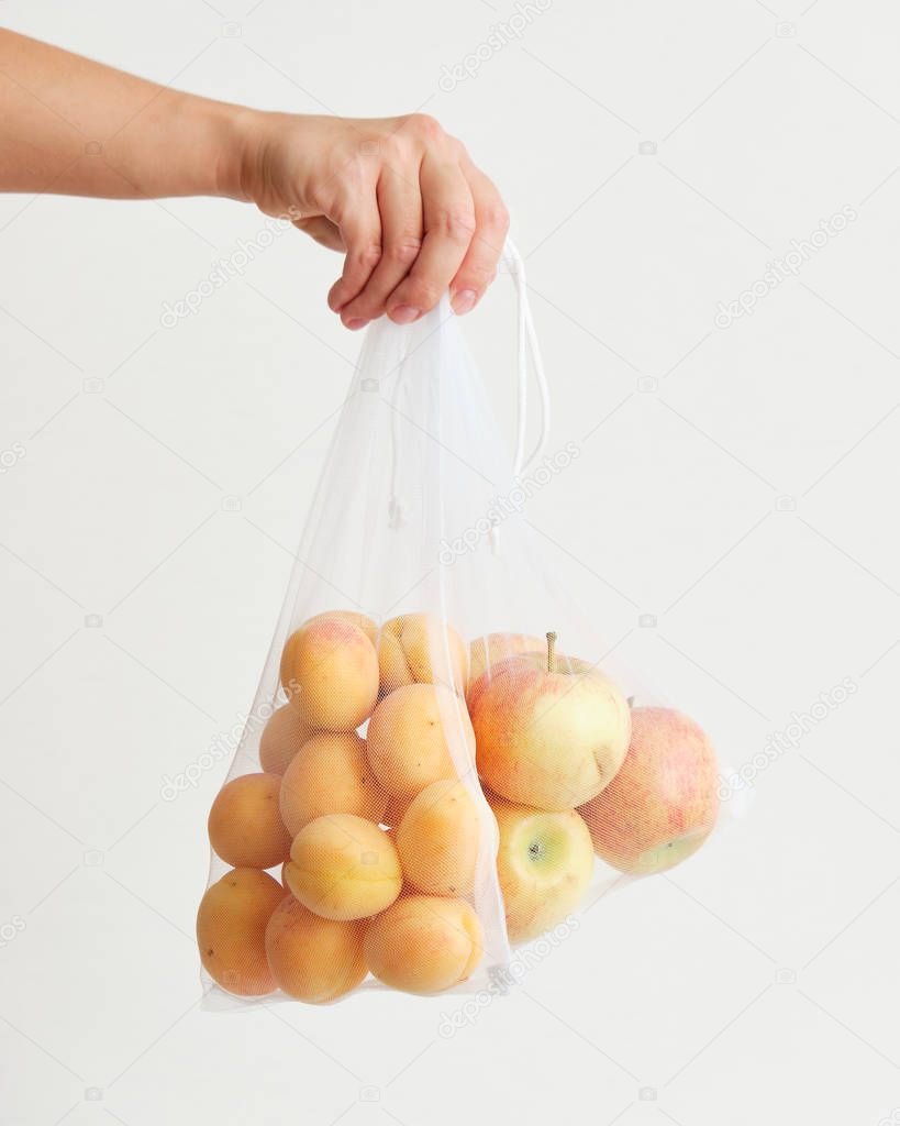 Hand Holding String Bag with Apples and Apricots