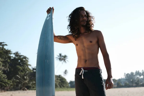 Surfista uomo seduto alla tavola da surf sulla spiaggia di sabbia — Foto Stock