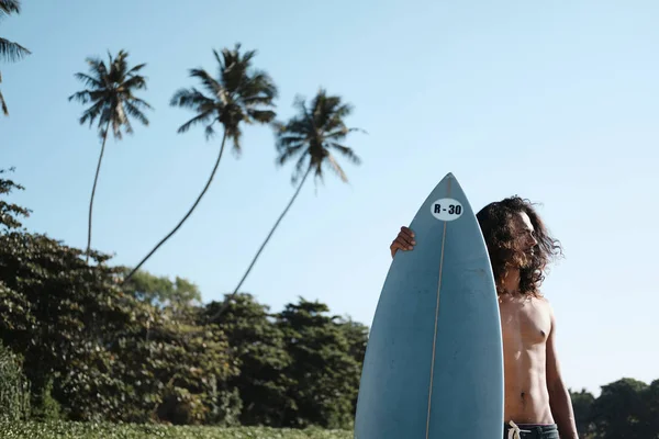 Hombre Surfista sentado en la tabla de surf en la playa de arena —  Fotos de Stock