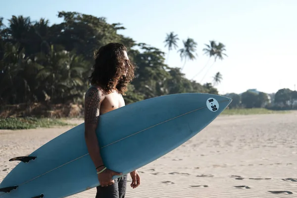 Homem surfista sentado na prancha de surf na praia de areia — Fotografia de Stock