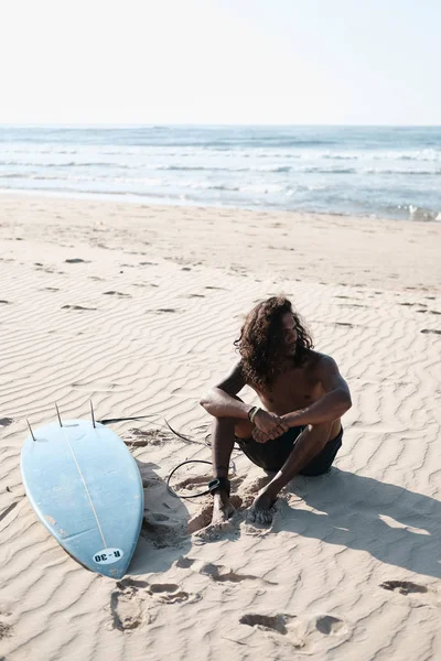 砂浜のサーフボードに座っている男サーファー — ストック写真