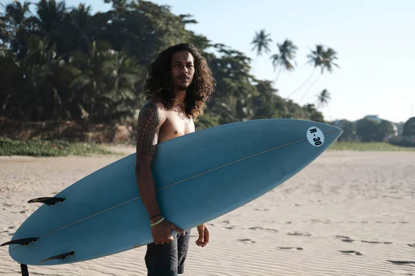 Hombre Surfista sentado en la tabla de surf en la playa de arena —  Fotos de Stock