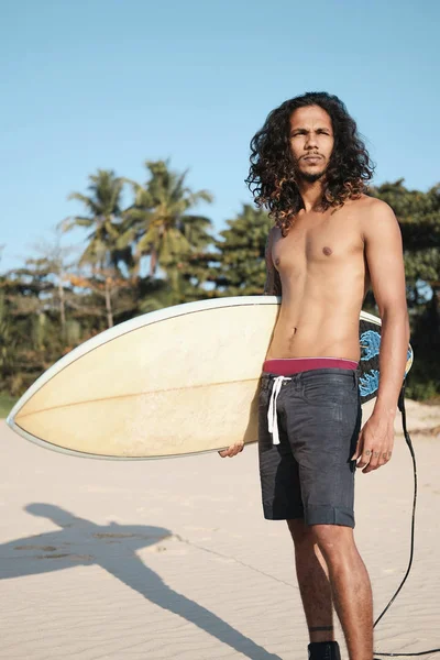 Surfista uomo seduto alla tavola da surf sulla spiaggia di sabbia — Foto Stock