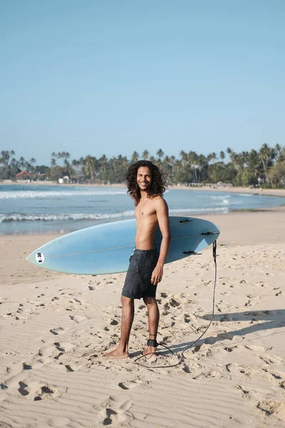 Hombre Surfista sentado en la tabla de surf en la playa de arena —  Fotos de Stock