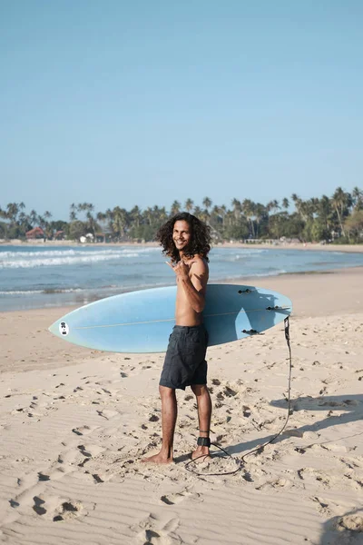 Hombre Surfista sentado en la tabla de surf en la playa de arena —  Fotos de Stock