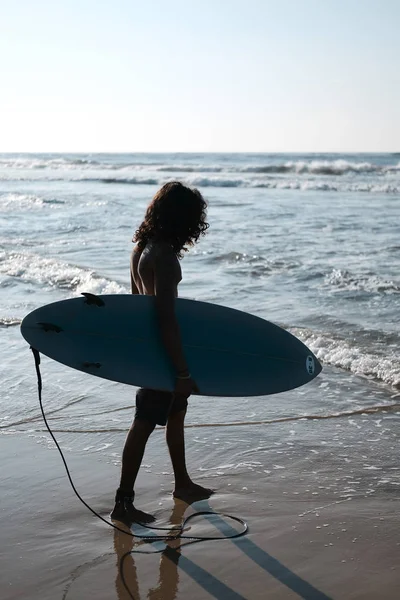 Surfista uomo seduto alla tavola da surf sulla spiaggia di sabbia — Foto Stock