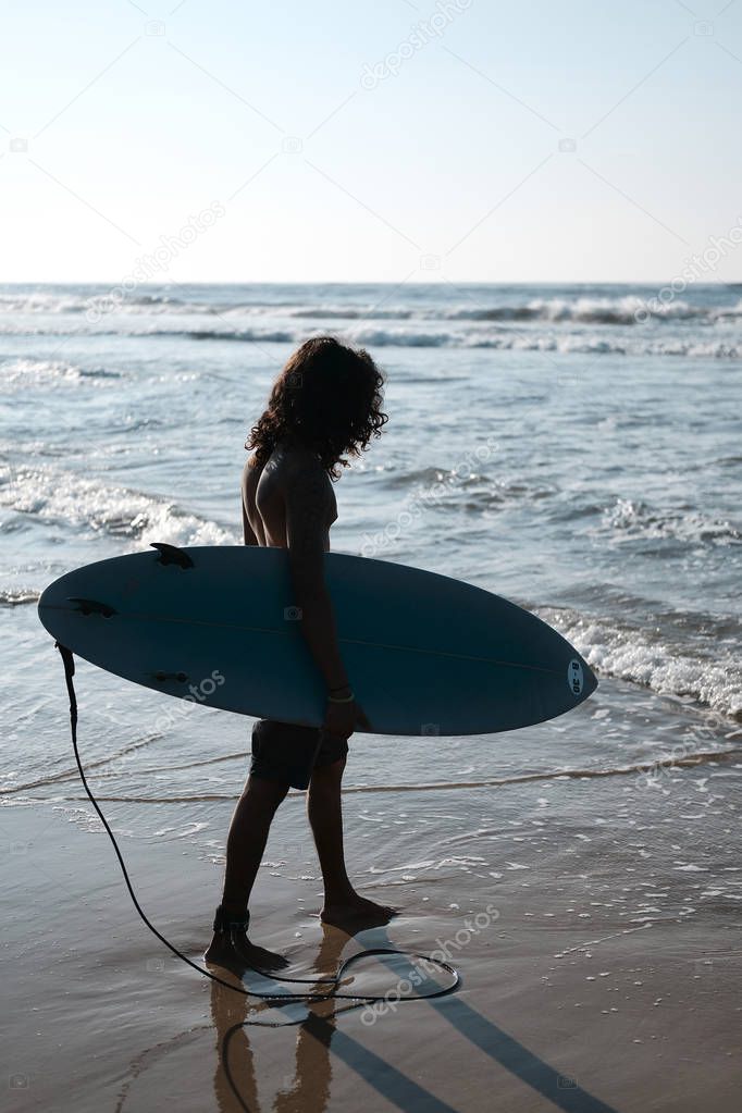 Man Surfer Sitting at Surfboard on Sand Beach