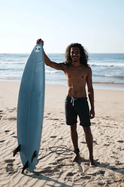 Surfista uomo seduto alla tavola da surf sulla spiaggia di sabbia — Foto Stock