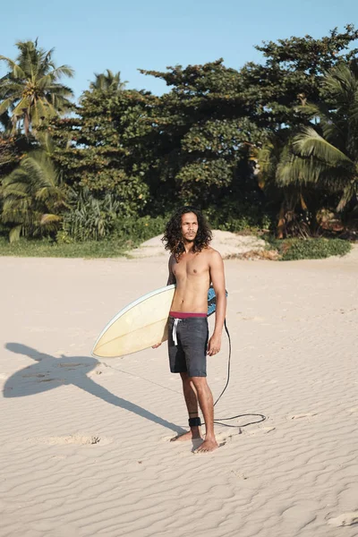 Hombre Surfista sentado en la tabla de surf en la playa de arena —  Fotos de Stock