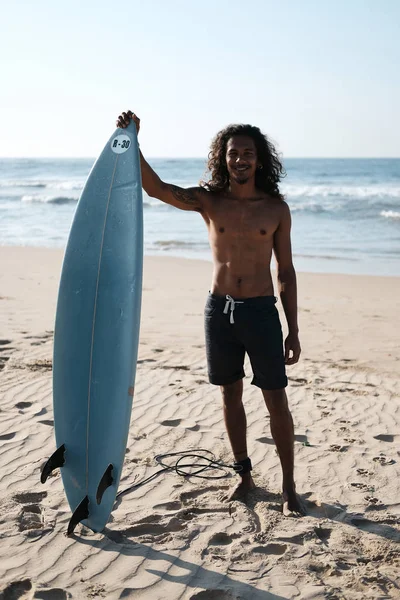 Surfista uomo seduto alla tavola da surf sulla spiaggia di sabbia — Foto Stock