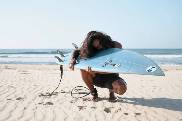 Homem surfista sentado na prancha de surf na praia de areia — Fotografia de Stock