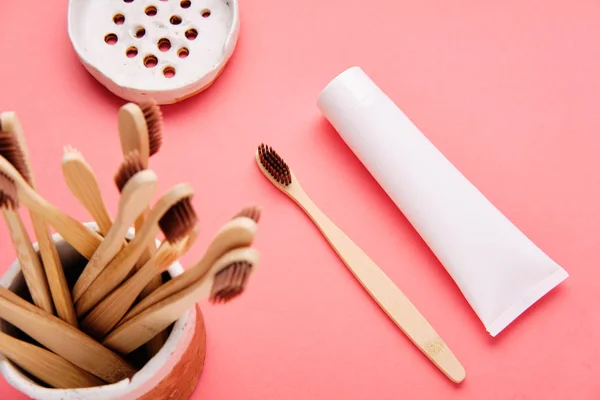 Escova de dentes de madeira com pasta de dentes em fundo rosa — Fotografia de Stock