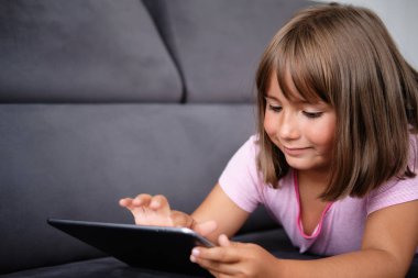 Anaokulu kızı tablete resim çizer. Küçük kız tabletle oynuyor.