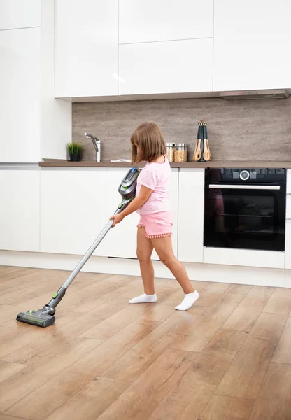 小女孩在房间里用吸尘器。吸尘和打扫房子。家务劳动 — 图库照片