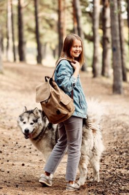 Genç kız ve köpeği Alaska Malamute, Sonbaharda açık havada. Evcil hayvan