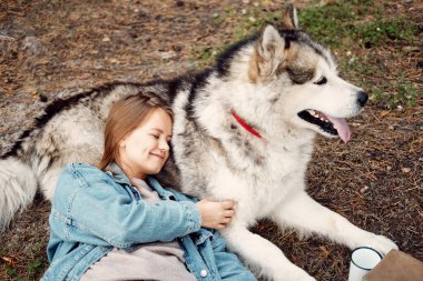 Genç kız ve köpeği Alaska Malamute, Sonbaharda açık havada. Evcil hayvan