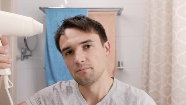 El joven sopla el cabello en un cuarto de baño. — Vídeos de Stock