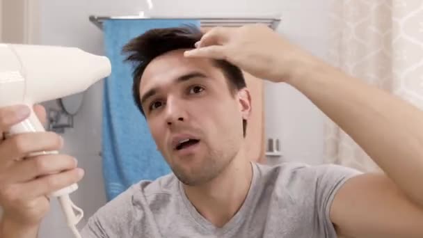 Молодой человек высушил волосы в ванной комнате — стоковое видео