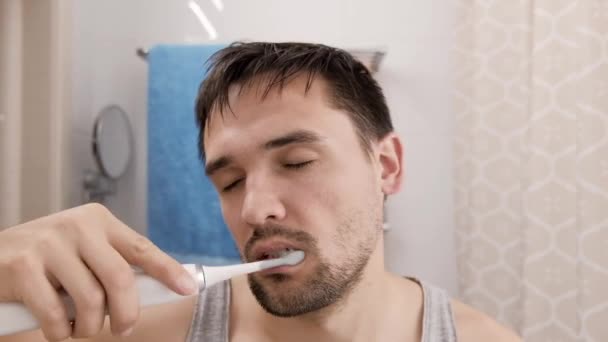 Hombre joven dormido y resplandeciente que tira los dientes en el baño. — Vídeo de stock
