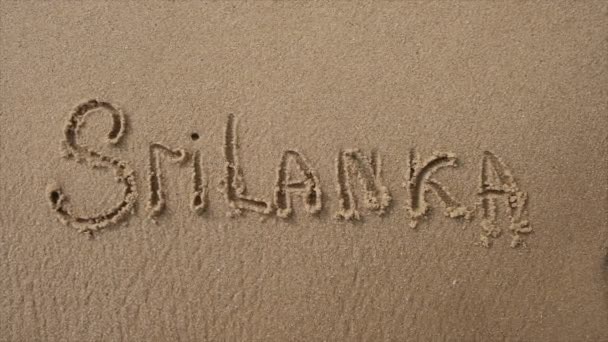 En våg spolas bort Ordet Sri Lanka skrivet i sanden — Stockvideo