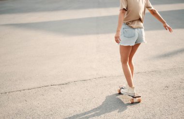 Longboard 'lu genç kadın. Güneşli havada sörf tahtasında poz veren kız patenci.