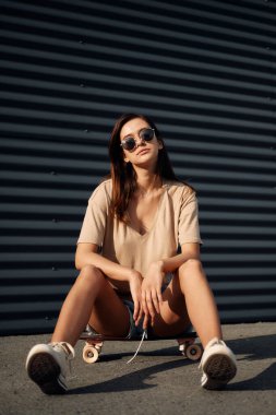 Longboard 'lu genç kadın. Güneşli havada sörf tahtasında poz veren kız patenci.