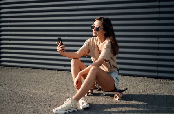 Giovane donna con Longboard. Ragazza pattinatrice posa sul longboard nel tempo soleggiato — Foto Stock