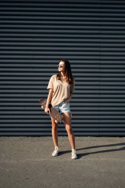 Giovane donna con Longboard. Ragazza pattinatrice posa sul longboard nel tempo soleggiato — Foto Stock