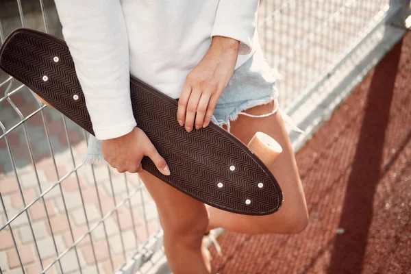 Junge Frau mit Longboard. Skaterin posiert bei sonnigem Wetter auf Longboard — Stockfoto