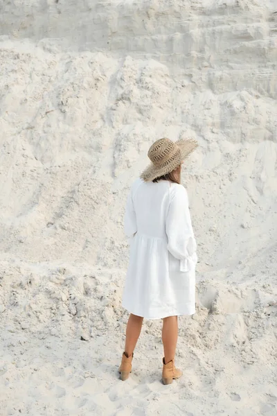 Elegante ragazza in biancheria alla moda estate vestito cappello di paglia in posa sulla sabbia. Stile Boho — Foto Stock