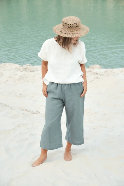 Ragazza elegante in abiti di lino e cappello di paglia. Relax in spiaggia, semplice stile slow life — Foto Stock