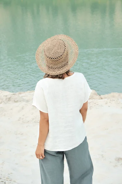 リネンの服やわらの帽子でスタイリッシュな女の子。ビーチでリラックスし、シンプルなスローライフスタイル — ストック写真