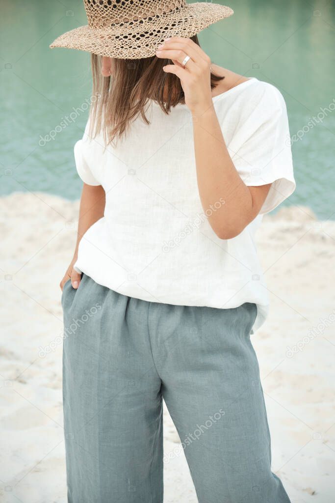 Stylish girl in linen clothes and straw hat. Relaxing in beach, simple slow life style. Culottes
