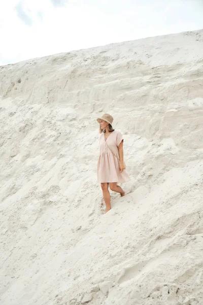 Menina elegante na moda vestido de linho de verão com chapéu de palha e saco posando na areia. Roupa de verão — Fotografia de Stock