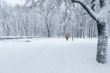 Kapıcı kışın parkta kürek ile