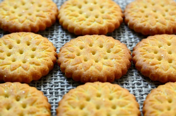 Round delicious salty crackers cookies on a burlap cloth as a background.Crispy baking.Classic snack concept.Selective focus.