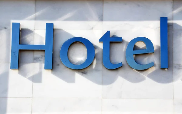 Hotel word with silver letters on a white stone wall background.Travel or tourism concept.