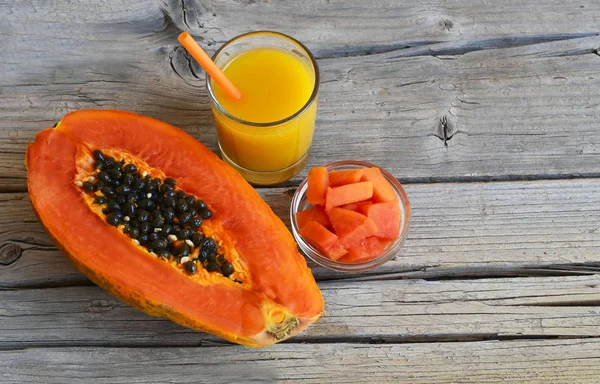 Fresh ripe organic papaya tropical fruit cut in half,sliced and papaya juice in a glass jar on old wooden background. Healthy eating,diet or vegan food concept.