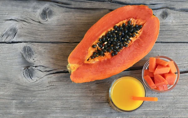 Fresh ripe organic papaya tropical fruit cut in half,sliced and papaya juice in a glass jar on old wooden background. Healthy eating,diet or vegan food concept.