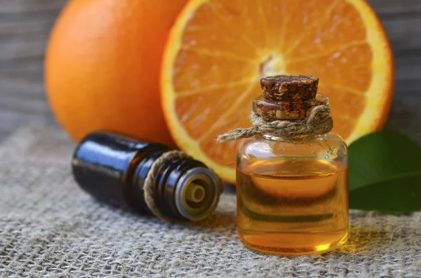 Orange essential oil in a glass bottle and fresh orange fruits on old wooden table.Citrus oil for skin care, spa, wellness, massage, aromatherapy and natural medicine.Selective focus.Copy space.