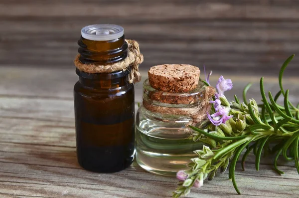 Rosemary essential oil in a glass dropper bottle with fresh green rosemary herb on old wooden table for spa,aromatherapy and bodycare.Copy space.