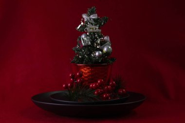 Kırmızı arka planda gümüş takılar olan küçük Noel Ağacı