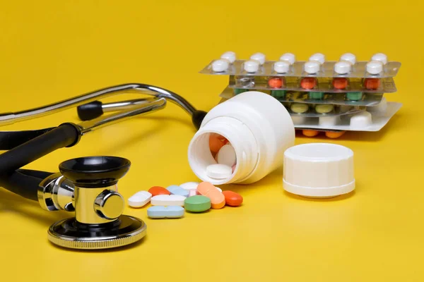 黄色背景上的药丸和听诊器 — 图库照片