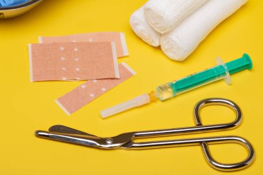 Sıva ve bandaj makas ve sarı bir arka plan üzerinde şırınga ile