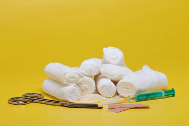 Sıva ve bandaj makas ve sarı bir arka plan üzerinde şırınga ile