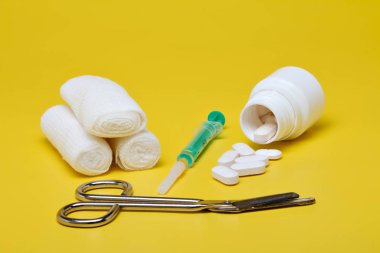 Sıva ve bandaj makas ve sarı bir arka plan üzerinde şırınga ile