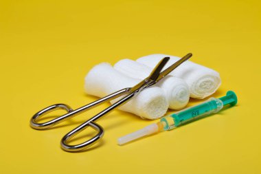 Sıva ve bandaj makas ve sarı bir arka plan üzerinde şırınga ile